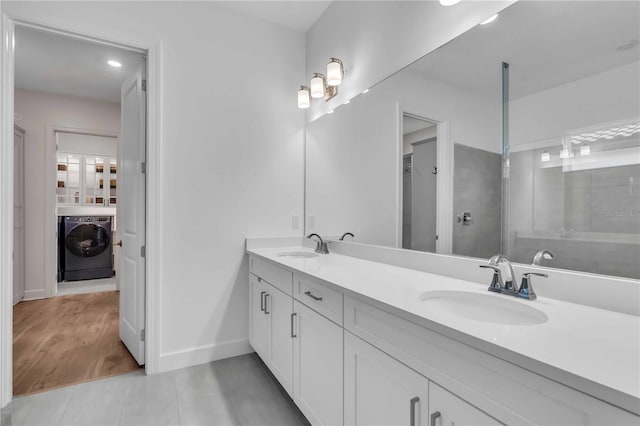 bathroom featuring vanity, washer / dryer, walk in shower, and tile patterned flooring