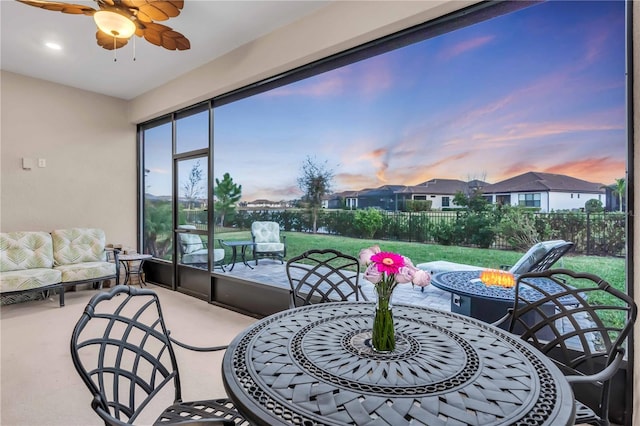 patio terrace at dusk featuring ceiling fan and an outdoor living space with a fire pit