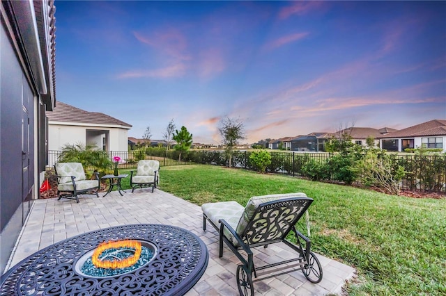 patio terrace at dusk featuring a lawn