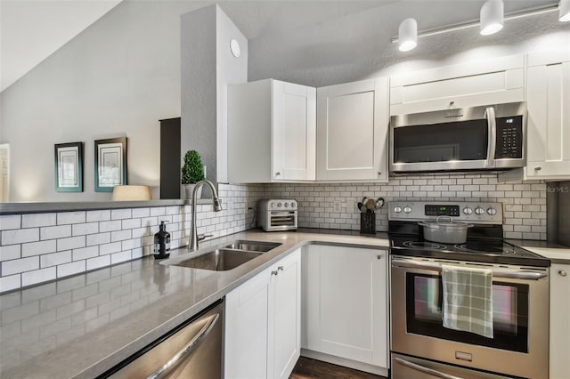 kitchen with appliances with stainless steel finishes, tasteful backsplash, sink, white cabinets, and light stone counters