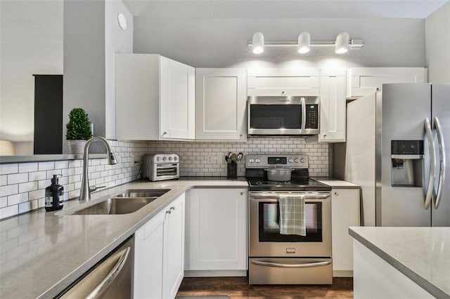 kitchen with white cabinetry, sink, backsplash, stainless steel appliances, and dark wood-type flooring