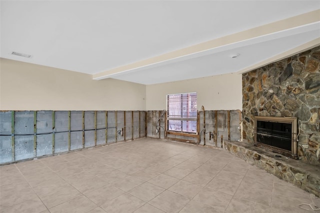 unfurnished living room with light tile patterned floors, beamed ceiling, and a fireplace