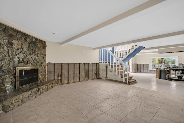 unfurnished living room featuring light tile patterned flooring, a stone fireplace, and beamed ceiling