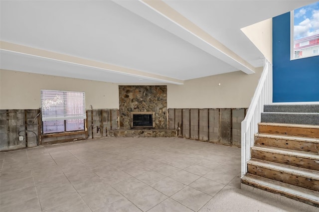 unfurnished living room with light tile patterned flooring, a fireplace, and beamed ceiling