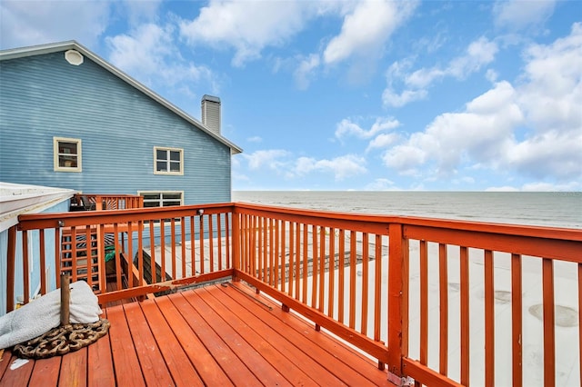 wooden terrace featuring a water view and a beach view