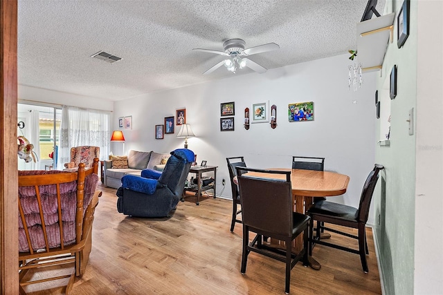 dining space with ceiling fan, a textured ceiling, and light hardwood / wood-style flooring