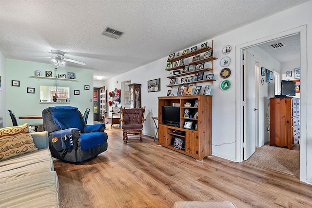 living room featuring a textured ceiling, ceiling fan, and hardwood / wood-style floors