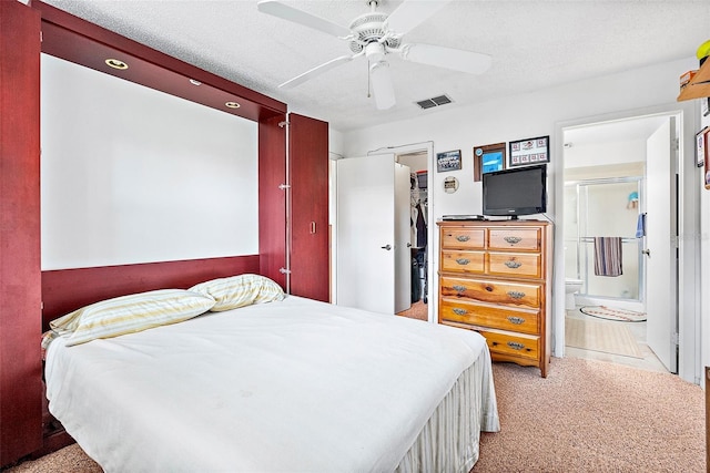 carpeted bedroom with ceiling fan, a closet, ensuite bathroom, and a textured ceiling