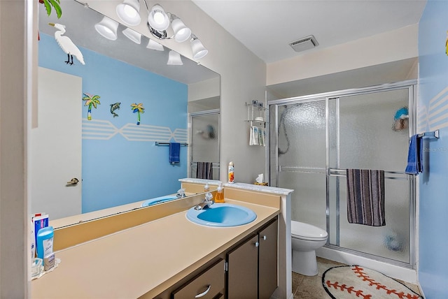 bathroom featuring walk in shower, vanity, tile patterned floors, and toilet