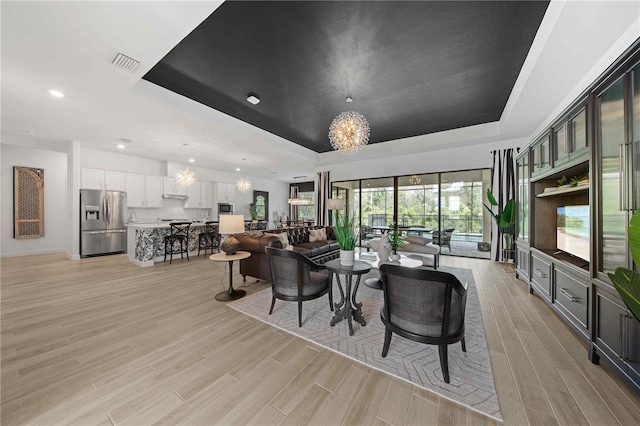 living room with a raised ceiling and an inviting chandelier