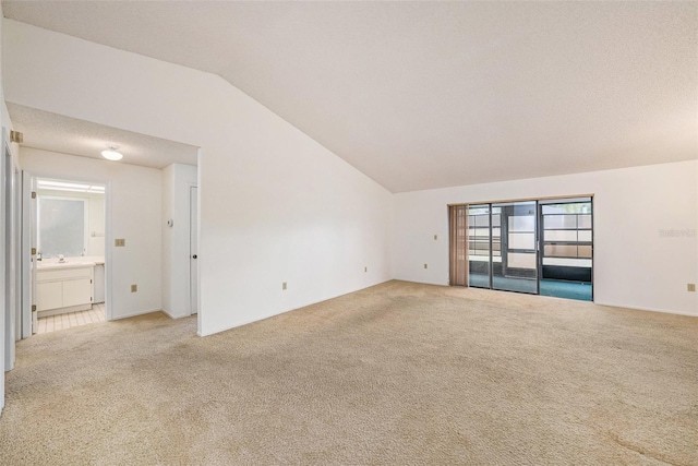 unfurnished living room featuring sink, vaulted ceiling, and light carpet