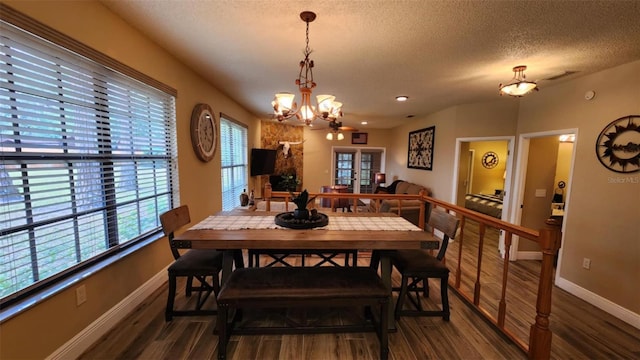 dining room with dark hardwood / wood-style flooring, a textured ceiling, and a notable chandelier