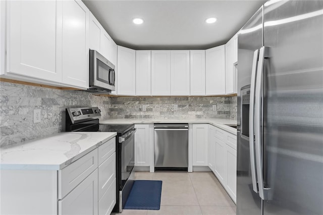 kitchen with white cabinetry, light stone countertops, appliances with stainless steel finishes, and light tile patterned floors