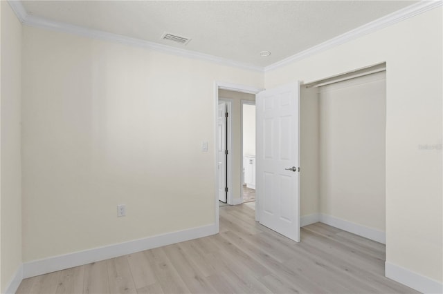 unfurnished bedroom with ornamental molding, light hardwood / wood-style floors, a closet, and a textured ceiling