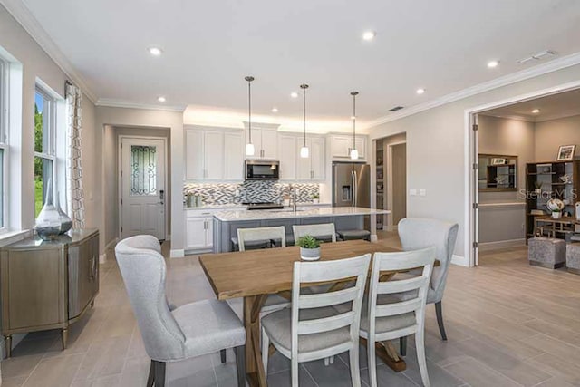 dining space with crown molding and sink