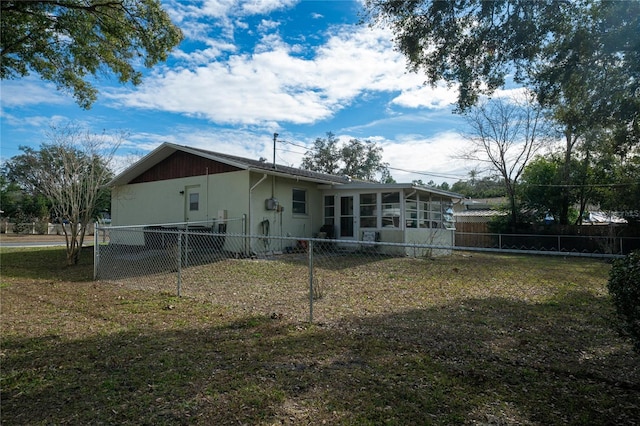 back of house featuring a lawn and a sunroom