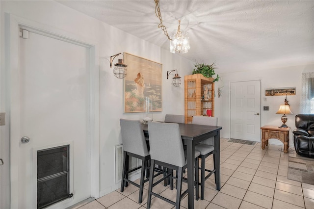 tiled dining space featuring a chandelier and a textured ceiling