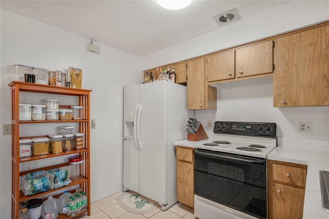 kitchen with light tile patterned flooring, white fridge with ice dispenser, a textured ceiling, and electric range