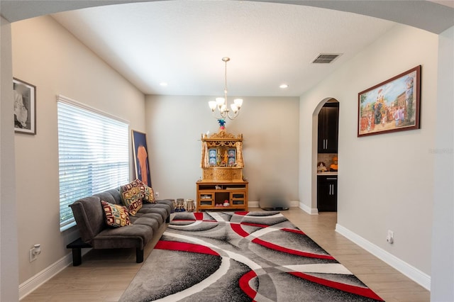 living room featuring a chandelier, a healthy amount of sunlight, and light hardwood / wood-style flooring