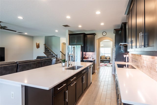 kitchen with sink, ceiling fan, decorative backsplash, an island with sink, and stainless steel appliances