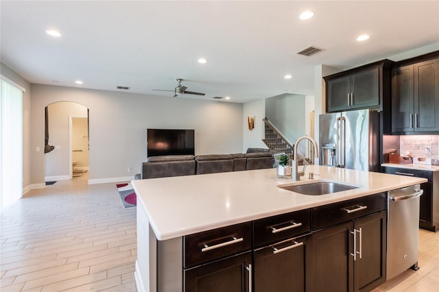 kitchen with a center island with sink, sink, ceiling fan, light hardwood / wood-style floors, and stainless steel appliances