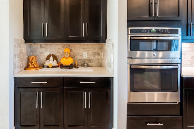 kitchen with decorative backsplash, dark brown cabinetry, and stainless steel double oven