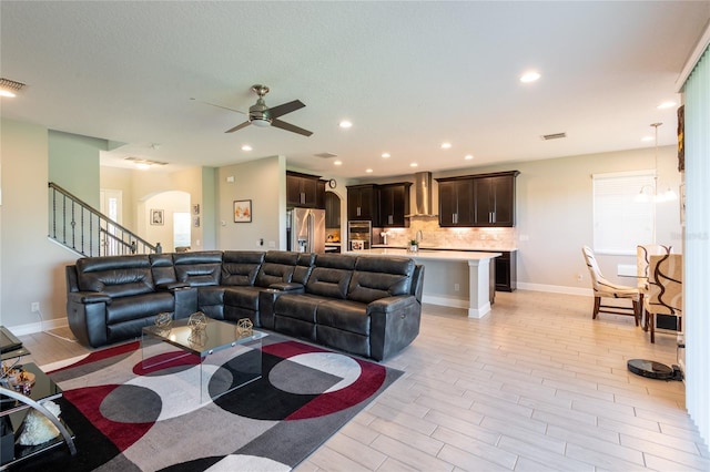 living room with ceiling fan with notable chandelier and sink