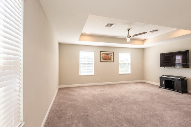 unfurnished living room featuring ceiling fan, light colored carpet, and a tray ceiling