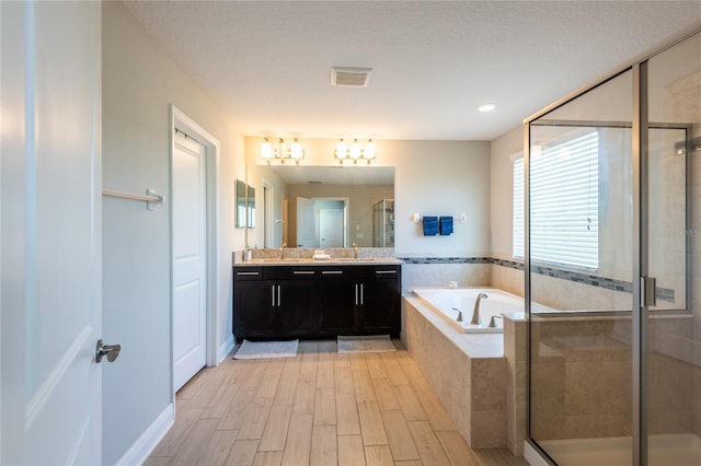 bathroom with vanity, separate shower and tub, and a textured ceiling