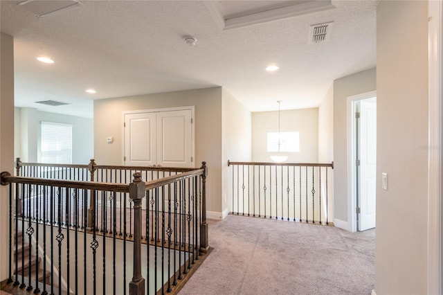 hallway with carpet flooring and a textured ceiling