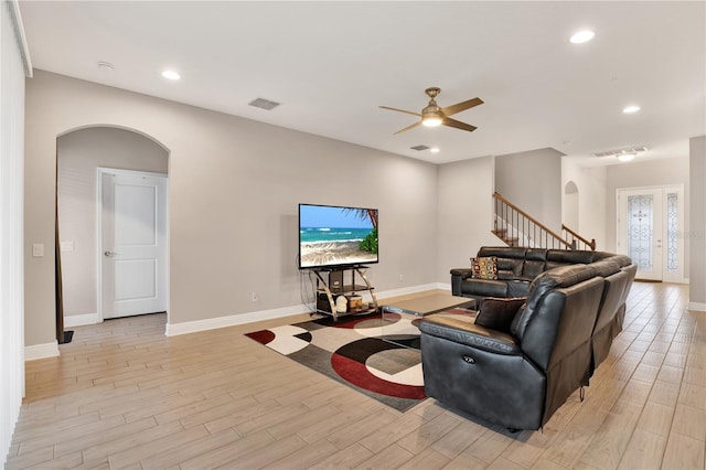 living area featuring arched walkways, visible vents, light wood-style flooring, and recessed lighting