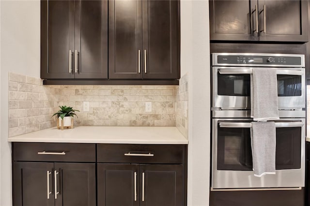 kitchen with double oven, light countertops, dark brown cabinetry, and tasteful backsplash