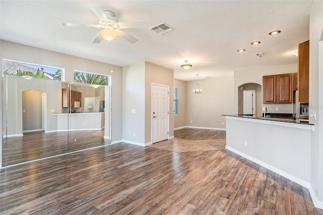 kitchen with hanging light fixtures, dark hardwood / wood-style flooring, ceiling fan with notable chandelier, a textured ceiling, and sink