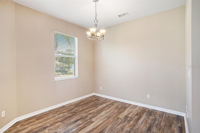 unfurnished room with an inviting chandelier and hardwood / wood-style flooring