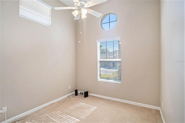 carpeted empty room with ceiling fan and a high ceiling