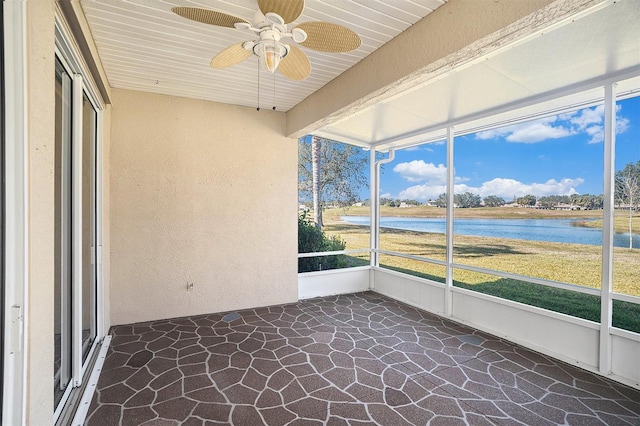 unfurnished sunroom featuring ceiling fan, a wealth of natural light, and a water view