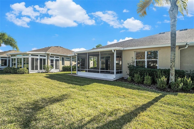 rear view of property with a lawn and a sunroom