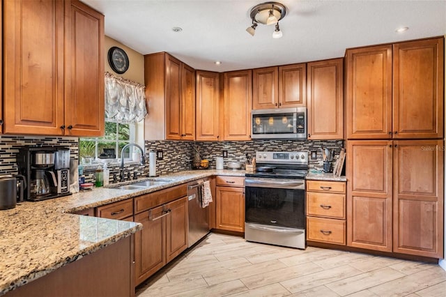 kitchen with backsplash, light hardwood / wood-style floors, sink, appliances with stainless steel finishes, and light stone counters