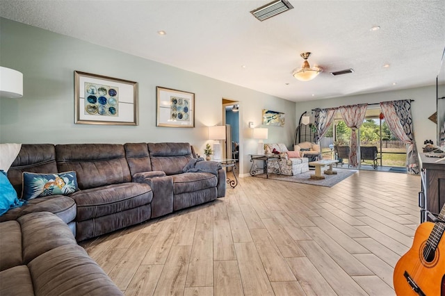 living room featuring a textured ceiling, ceiling fan, and light hardwood / wood-style flooring