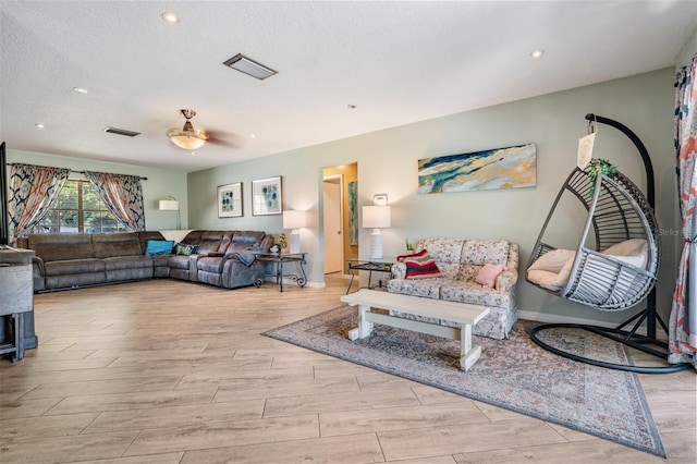 living room featuring ceiling fan and a textured ceiling