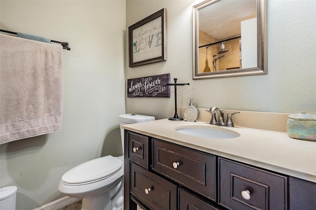 bathroom featuring a shower, toilet, and vanity