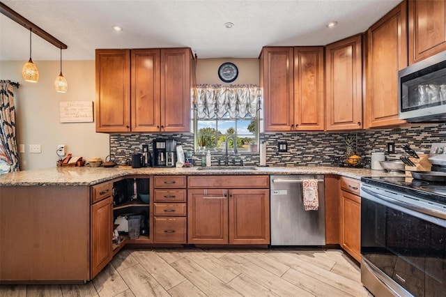 kitchen with light stone countertops, stainless steel appliances, sink, kitchen peninsula, and light wood-type flooring