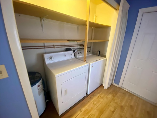 laundry area featuring independent washer and dryer, electric water heater, and light hardwood / wood-style flooring