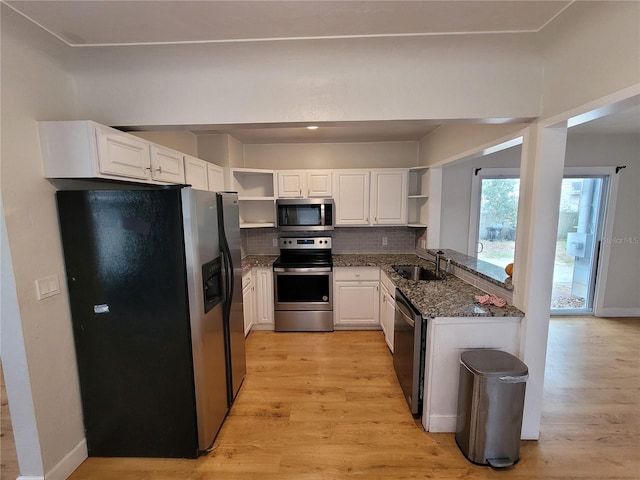 kitchen with dark stone countertops, appliances with stainless steel finishes, decorative backsplash, white cabinets, and sink