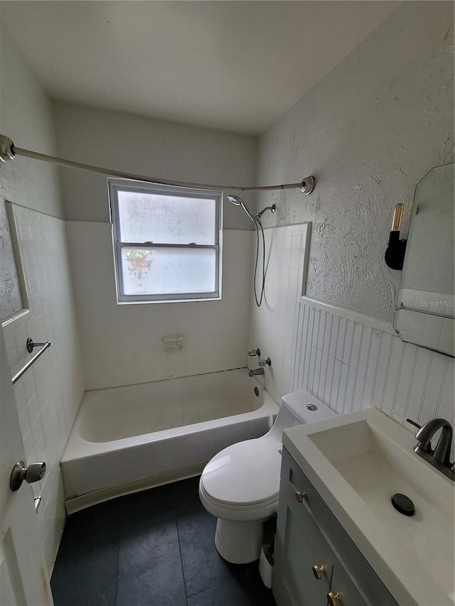 full bathroom with tile patterned flooring, tiled shower / bath combo, vanity, and toilet