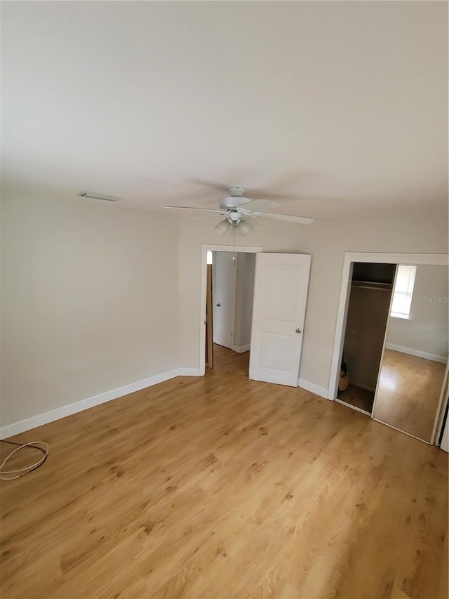 unfurnished bedroom with light wood-type flooring, ceiling fan, and a closet