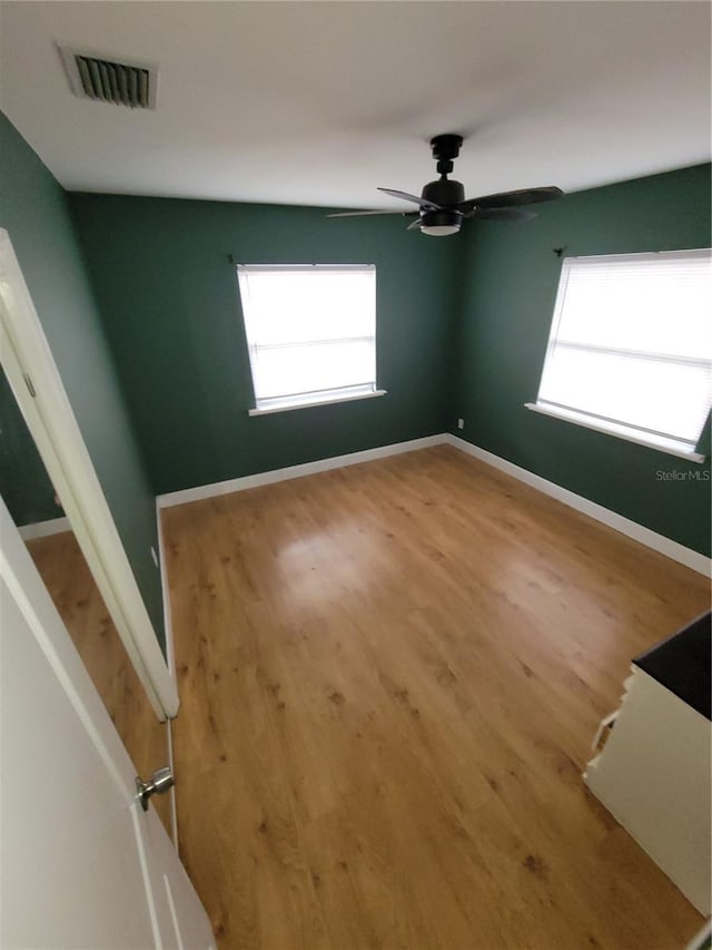 unfurnished room featuring ceiling fan, plenty of natural light, and hardwood / wood-style flooring