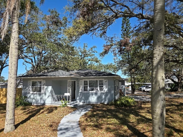 view of front of home featuring covered porch, a front yard, and fence