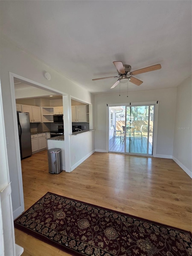 unfurnished living room with a ceiling fan, light wood-style flooring, and baseboards