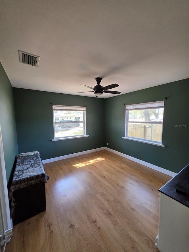 unfurnished bedroom with baseboards, visible vents, ceiling fan, and wood finished floors